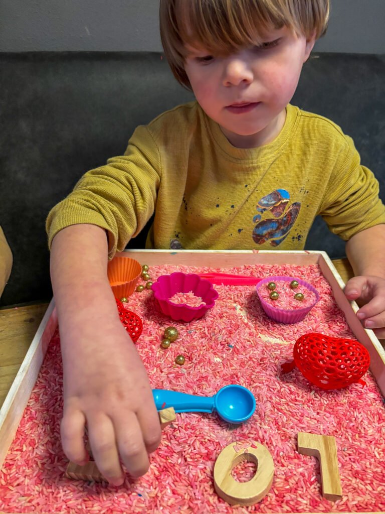 luan speelt ontspannen met een sensorische speelbak vol gekleurde rijst – voorbeeld van open spel na schooltijd